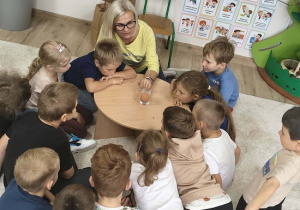dzieci słuchają nauczycielki, która tłumaczy doświadczenie