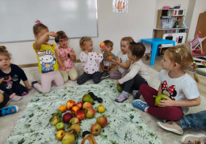 dzieci z owocami siedzą na dywanie