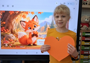 dziecko prezentuje swoje wycięte pomarańczowe serduszko