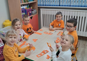 dzieci siedzą przy stolikach i wycinają serduszka