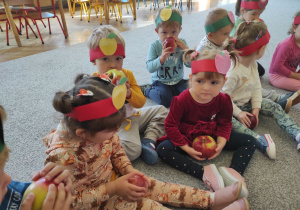 dzieci siedzą z jabłkami na dywanie