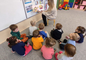 dzieci siedzą na dywanie i słuchają opowiadania