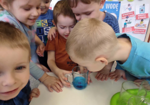 dzieci oglądają niebieską wodę w szklance