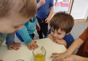 dzieci oglądają szklankę z żółtą wodą