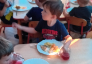 dzieci siedzą przy stolikach podczas posiłku