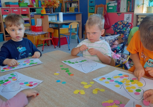 dzieci wyklejają motyla kolorowymi kropkami