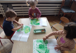 dzieci kolorują kredkami plakat z drzewami