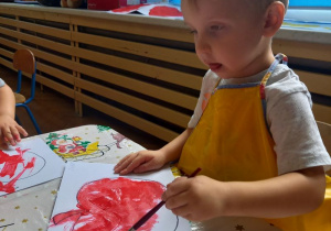 chłopiec maluje czerwoną farbą jabłko