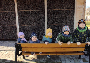dzieci siedzą na ławeczkach przy tężni