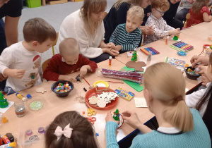 rodzice wspólnie z dziećmi ozdabiają styropianowe choinki