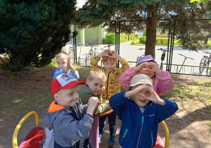 dzieci bujają się na karuzeli i pokazują serce z dłoni