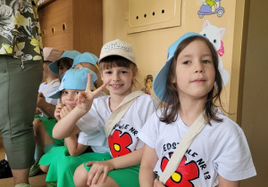 dziewczynki w kolorowych strojach siedzą na ławeczce