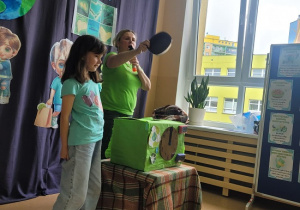 dziewczynka wrzuca śmieci do pudełka z wizerunkiem zegara