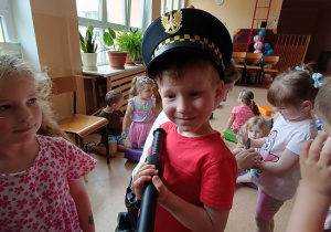 chłopiec w czapce strażnika z pałką policyjną