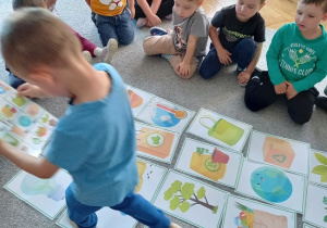 chłopiec chodzi po zakodowanej trasie obrazków ilustrujących elementy ziemi