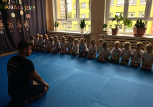 dzieci siedzą w grupie na zajęciach judo