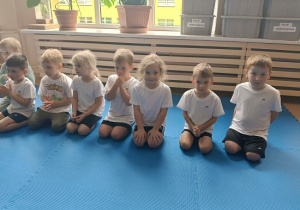 dzieci siedzą w grupie na zajęciach judo
