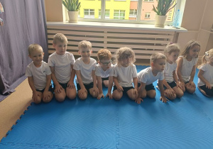 dzieci siedzą w grupie na zajęciach judo