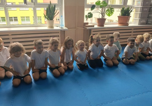 dzieci siedzą w grupie na zajęciach judo