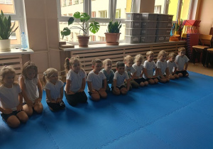 dzieci siedzą w grupie na zajęciach judo