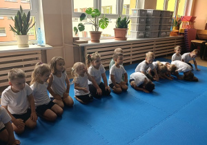dzieci siedzą w grupie na zajęciach judo