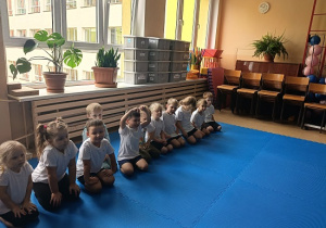 dzieci siedzą w grupie na zajęciach judo