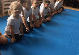 dzieci siedzą w grupie na zajęciach judo