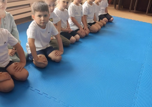 dzieci siedzą w grupie na zajęciach judo