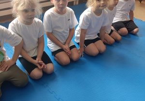 dzieci siedzą w grupie na zajęciach judo