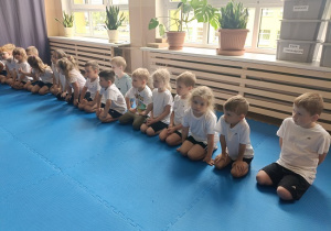 dzieci siedzą w grupie na zajęciach judo