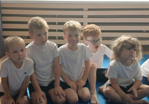 dzieci siedzą w grupie na zajęciach judo