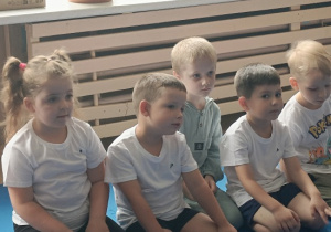 dzieci siedzą w grupie na zajęciach judo