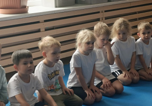 dzieci siedzą w grupie na zajęciach judo