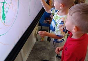 chłopcy rysują na tablicy interaktywnej