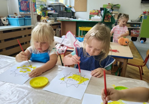 dziewczynki malują żółtą farbą szablon słoneczka