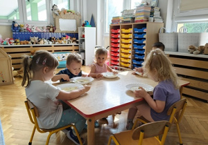 dzieci siedzą przy stoliku i jedzą zupę