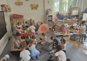 dzieci z Panią bawią się zabawkami na podłodze