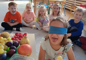 dziewczynka z opaską na oczach smakuje owoc
