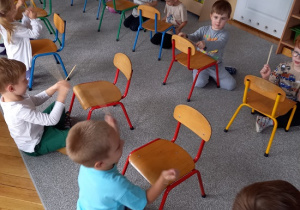 dzieci grają na łyżkach, przed nimi stoją krzesełka