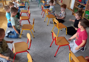 dzieci siedzą przed krzesełkami