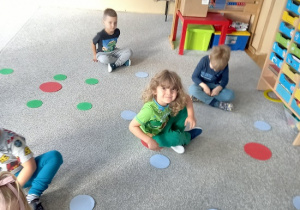 dzieci siedzą na kolorowych kropkach