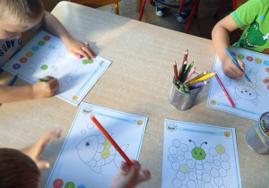 dzieci siedzą przy stoliku i wykonują kartę pracy