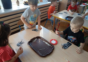 dzieci wyklejają szkielet dłoni papierowej patyczkami kosmetycznymi