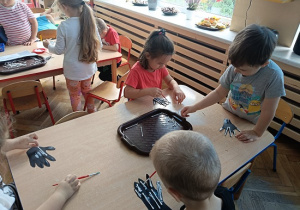 dzieci wyklejają szkielet dłoni papierowej patyczkami kosmetycznymi