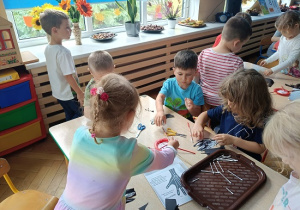 dzieci wyklejają szkielet dłoni papierowej patyczkami kosmetycznymi