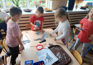 dzieci wyklejają szkielet dłoni papierowej patyczkami kosmetycznymi