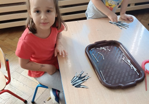 dzieci wyklejają szkielet dłoni papierowej patyczkami kosmetycznymi