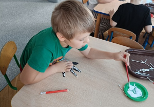 dzieci wyklejają szkielet dłoni papierowej patyczkami kosmetycznymi