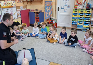 Pan strażak objaśnia dzieciom udzielanie pierwszej pomocy na fantomie