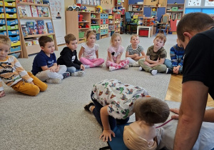 Pan strażak objaśnia dzieciom udzielanie pierwszej pomocy na fantomie